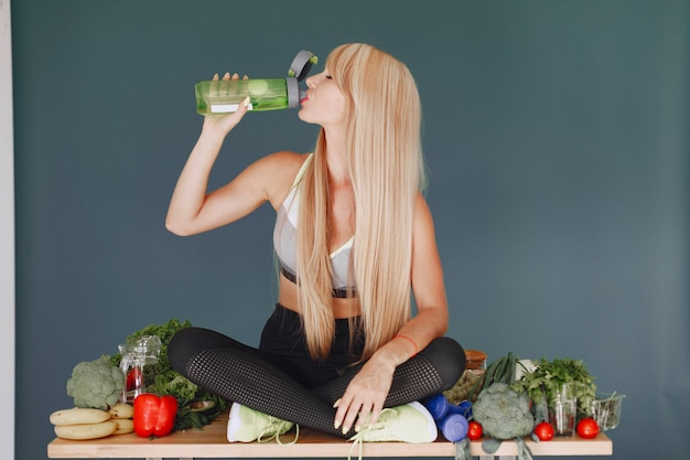 Ragazza bella e sportiva in una cucina con verdure