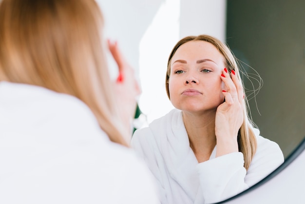 Ragazza bionda che applica la crema sul viso