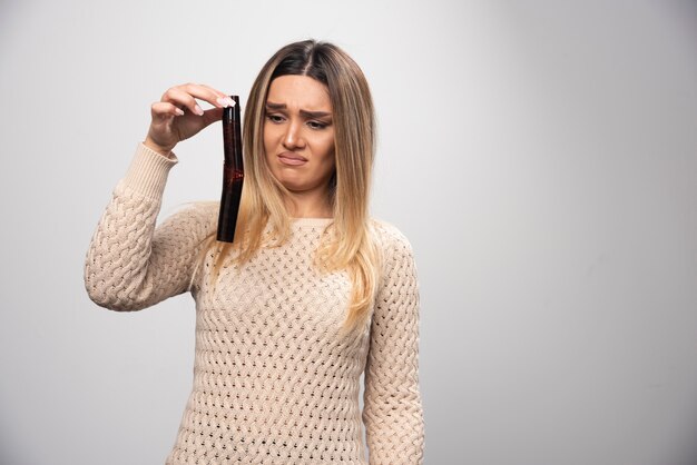 Ragazza bionda che controlla le foto sul rullino fotografico e si sente delusa.