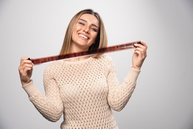 Ragazza bionda che controlla le foto sul rullino fotografico e si sente felice e positiva per il risultato.