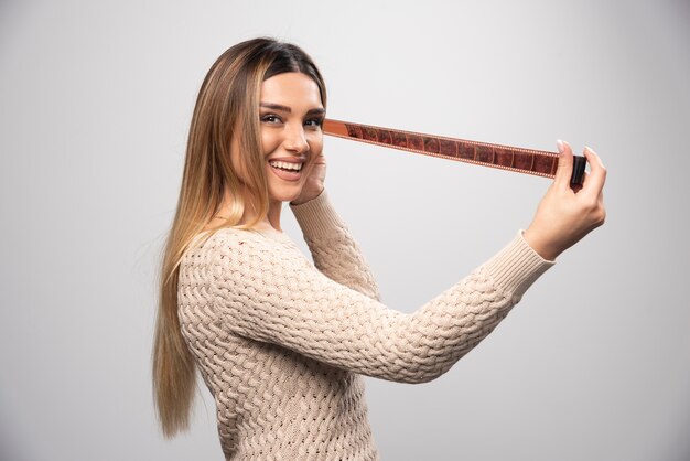 Ragazza bionda che controlla le foto sul rullino fotografico e si sente felice e positiva per il risultato.