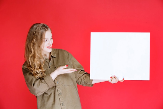 Ragazza bionda che dimostra un'opera d'arte su tela.