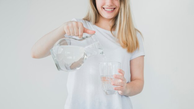 Ragazza bionda che riempie bicchiere d&#39;acqua