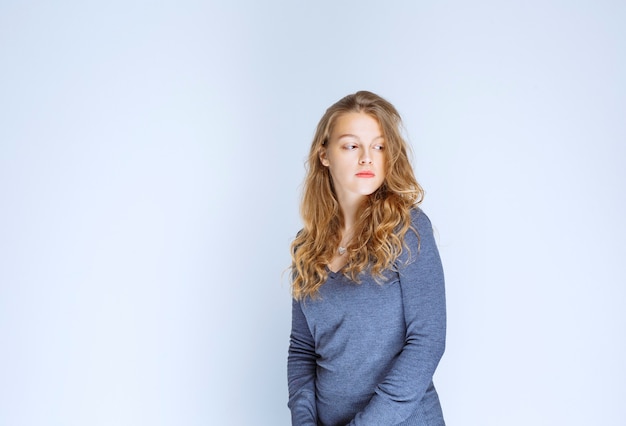 Ragazza bionda con i capelli ricci in posa in maglione indaco.