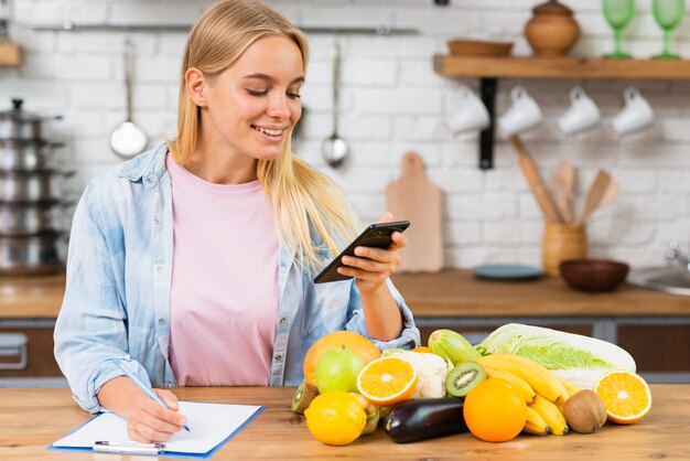 Ragazza bionda del colpo medio con lo smartphone