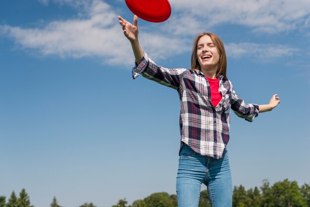 Ragazza bionda di angolo basso che gioca con un frisbee rosso