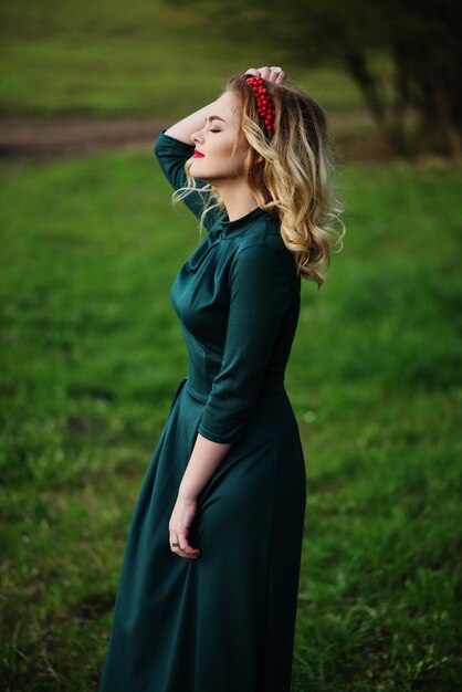 Ragazza bionda di eleganza di Yong al vestito verde sul giardino in primavera