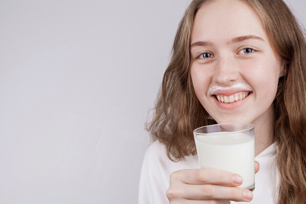 Ragazza bionda di vista frontale che tiene un bicchiere di latte