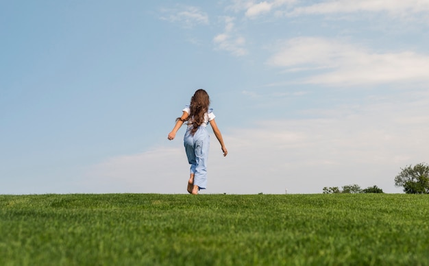 Ragazza bionda di vista posteriore che resta fuori