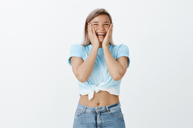 Ragazza bionda emozionante positiva che posa nello studio