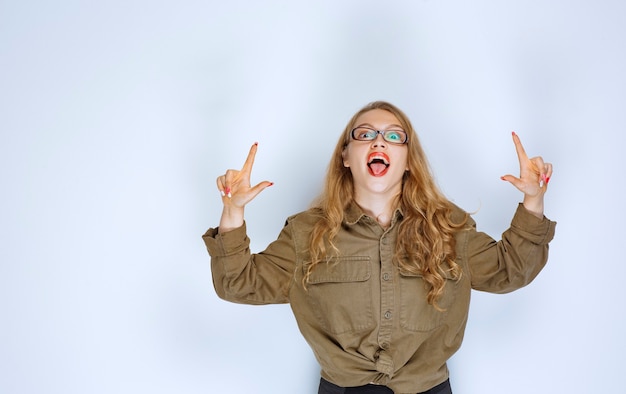 Ragazza bionda in camicia verde che indica sopra.