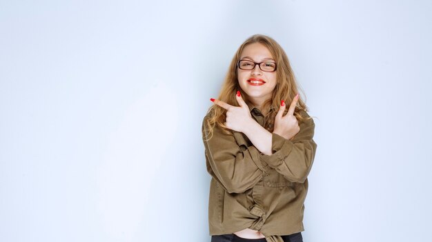 Ragazza bionda in camicia verde che indica sopra.