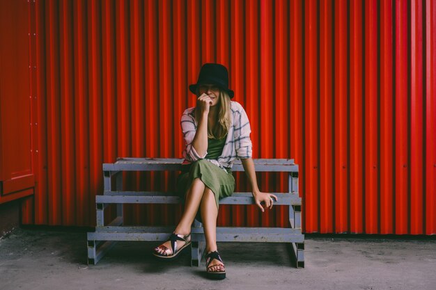 Ragazza bionda in un cappello. Foto della strada. Una bella ragazza che indossa abiti casual sorride misteriosamente. Stile vintage