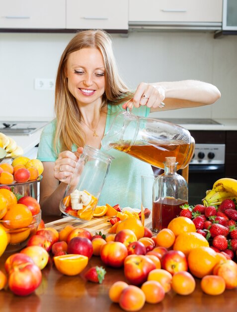 Ragazza bionda positiva che versa le bevande fresche