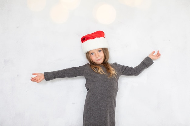 Ragazza bionda sveglia che porta un cappello del Babbo Natale