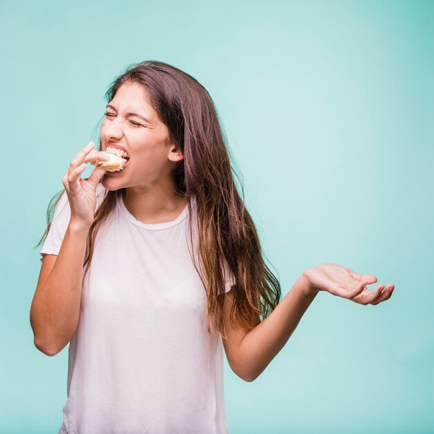 Ragazza bruna che mangia pasticceria