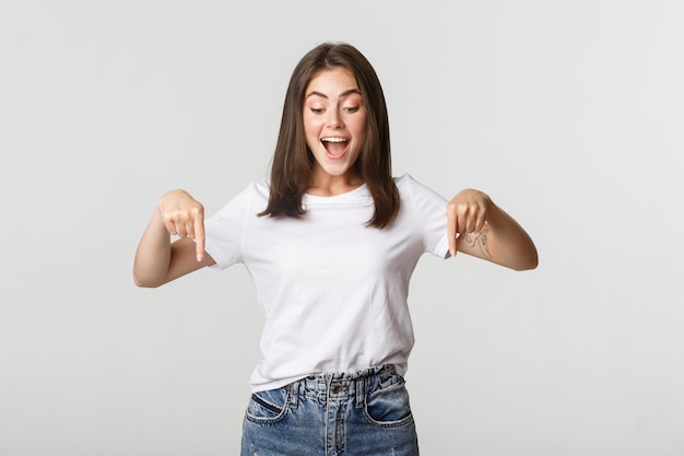 Ragazza bruna felice eccitata, guardando e rivolto verso il basso con un sorriso divertito.