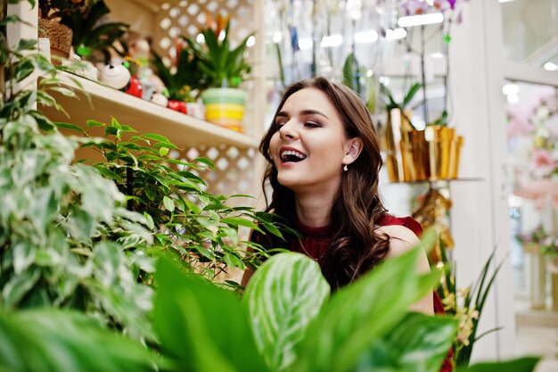 Ragazza bruna in rosso comprare fiori al negozio di fiori