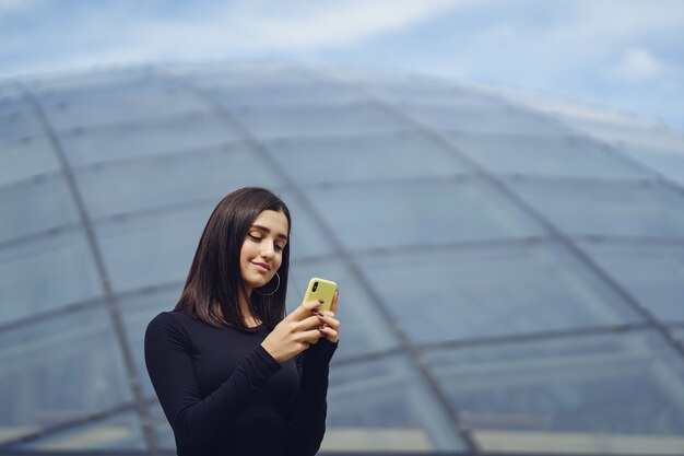 ragazza bruna usando il suo cellulare mentre sta esplorando una nuova città