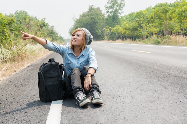 Ragazza calma seduto sulla strada e che punta a qualcosa