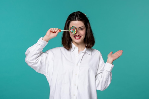 Ragazza carina bella bruna giovane ragazza dolce in camicia bianca che copre il viso con caramelle