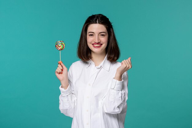 Ragazza carina bella bruna ragazza dolce in camicia bianca che tiene i pugni super eccitati