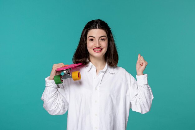 Ragazza carina bella giovane ragazza castana graziosa in camicia bianca che tiene i pugni in su