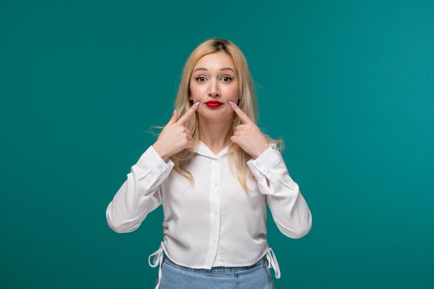 Ragazza carina bionda giovane ragazza carina in una camicia bianca che tiene le guance come un bambino