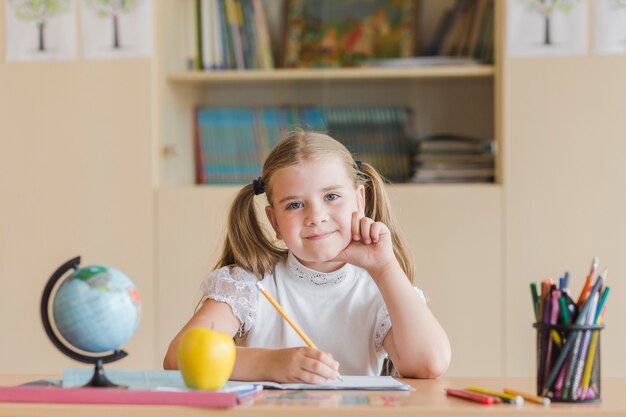 Ragazza carina che guarda l&#39;obbiettivo durante la lezione