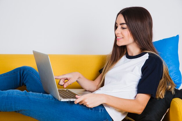 Ragazza carina che lavora sul divano