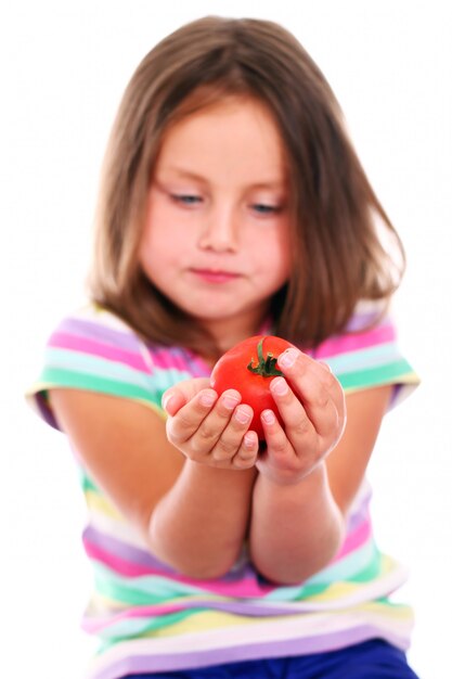 Ragazza carina che mangia un pomodoro