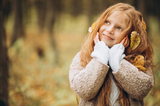 Ragazza carina con lunghi capelli rossi nella foresta autunnale