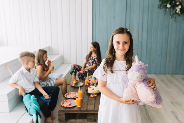 Ragazza carina con unicorno giocattolo sulla festa di compleanno