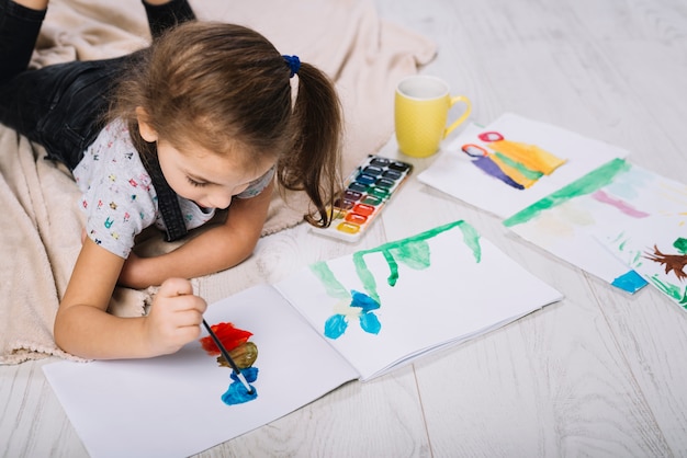 Ragazza carina dipinto con aquarelle brillante sul pavimento