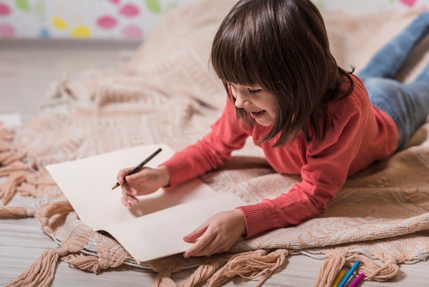 Ragazza carina disegno su carta sul pavimento