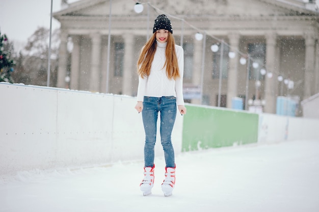 Ragazza carina e bella in un maglione bianco in una città d'inverno