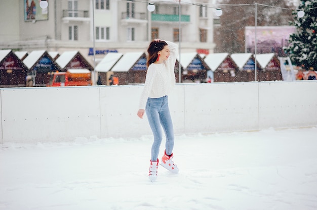 Ragazza carina e bella in un maglione bianco in una città d'inverno