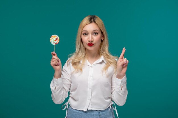 Ragazza carina giovane adorabile ragazza carina in una camicia bianca ordinata incrociando le dita tenendo una caramella