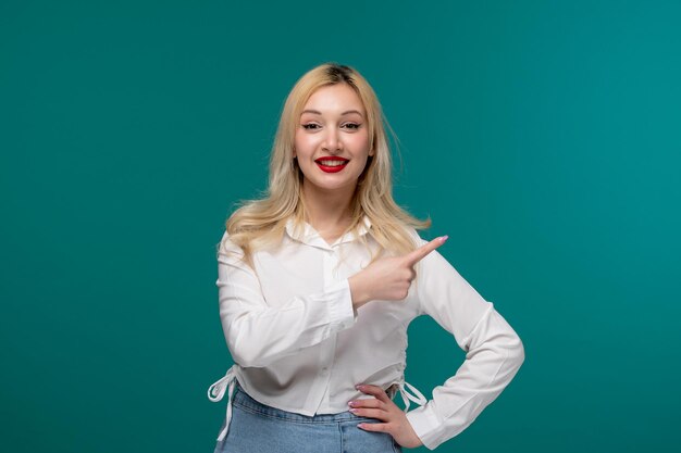 Ragazza carina giovane bella ragazza bionda in una camicia bianca che punta a sinistra e tenendo la mano sulla vita