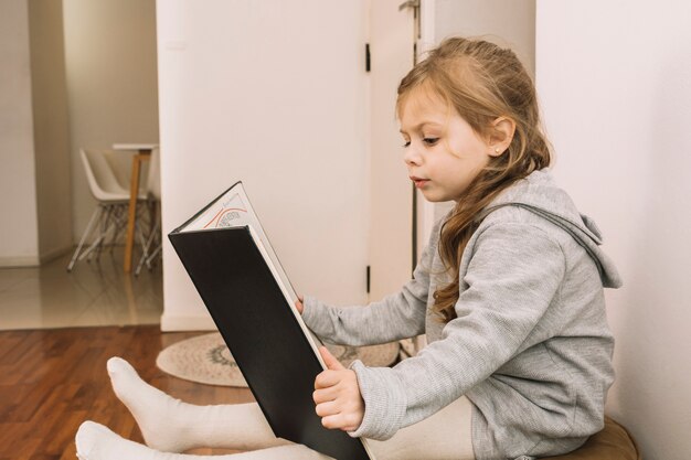 Ragazza carina godendo la lettura sul pouf