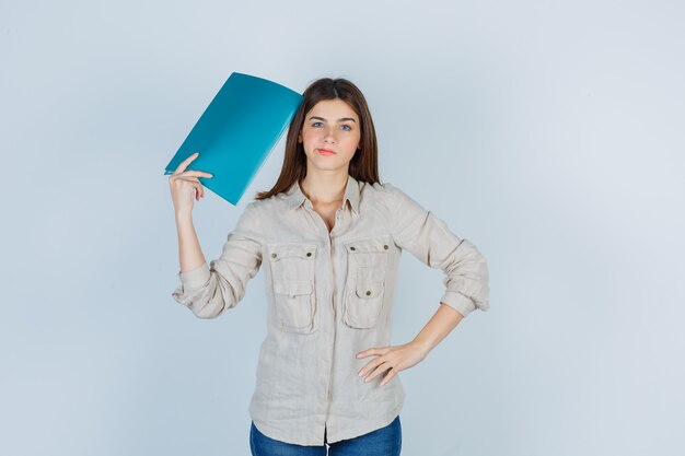 Ragazza carina in camicia che tiene la cartella e sembra premurosa