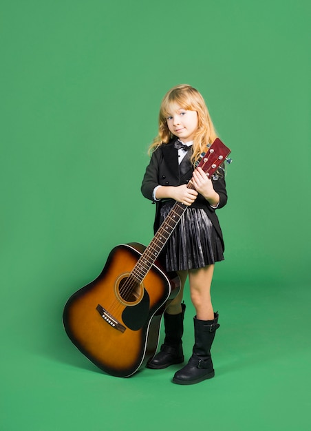 Ragazza carina in piedi con la chitarra acustica