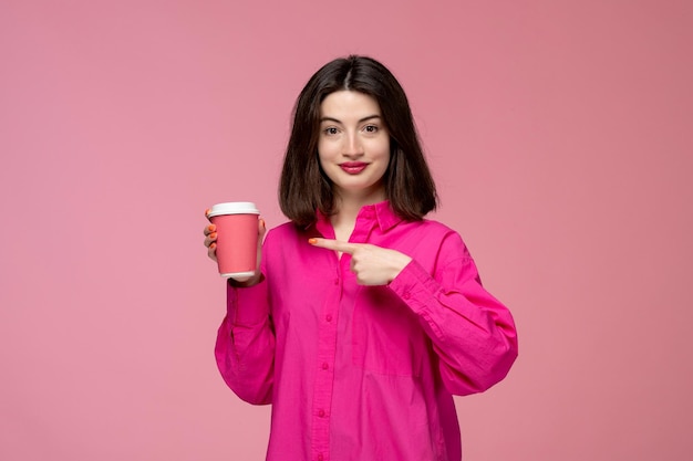 Ragazza carina piuttosto giovane bella ragazza bruna in camicia rosa che tiene una tazza di caffè rosa