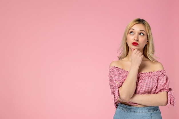 Ragazza carina ragazza adorabile che indossa rossetto rosso in camicetta rosa pensando e concentrata