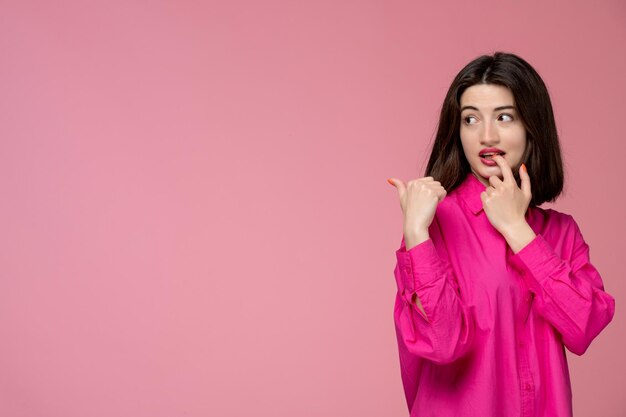 Ragazza carina ragazza adorabile in camicia rosa con rossetto rosso che morde il dito guardando dietro