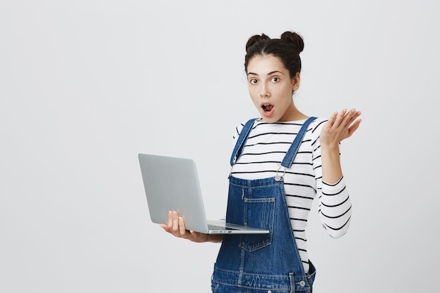 Ragazza carina sorpresa che sembra eccitata durante l'utilizzo del computer portatile