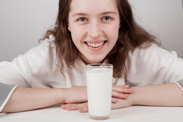 Ragazza carina sorridente accanto a un bicchiere di latte