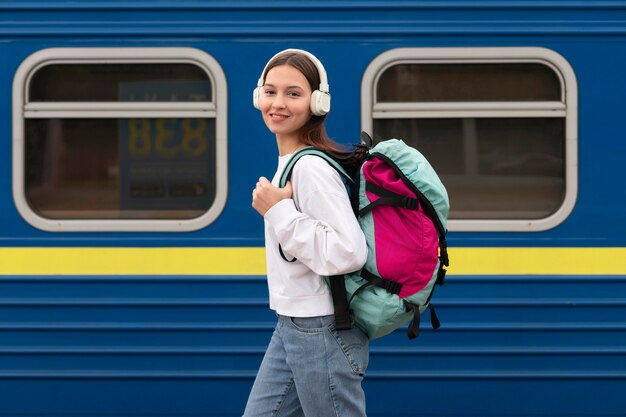 Ragazza carina vista laterale alla stazione ferroviaria ascoltando musica