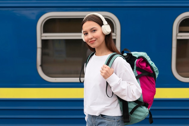 Ragazza carina vista laterale presso la stazione ferroviaria sorride