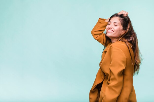 Ragazza castana sorridente che posa con il cappotto